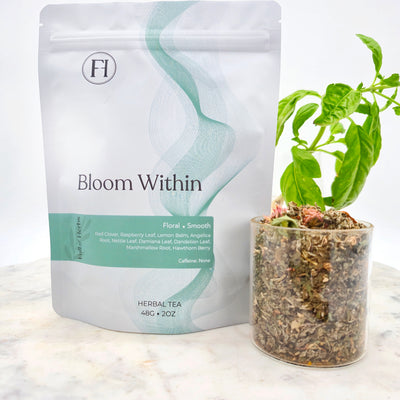 Herbal tea packaging labeled 'Bloom Within' with a small potted plant on a marble surface. Bloom Within organic PMS and hormone balance herbal tea