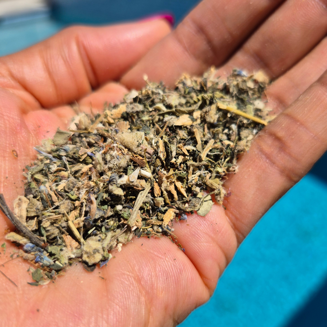 Hand holding a small amount of dried herbs against a blue background Clear & Free